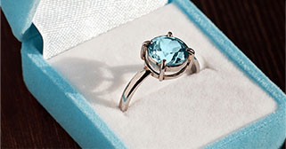 a ring with a blue topaz sits in a box