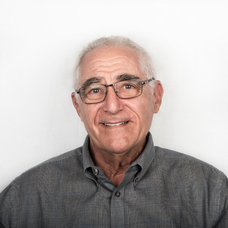 an older man with glasses smiling for the camera