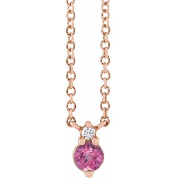 a necklace with a pink heart and two diamonds