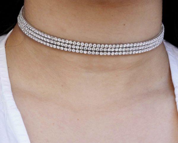 a woman wearing a white choker with three rows of diamonds on it