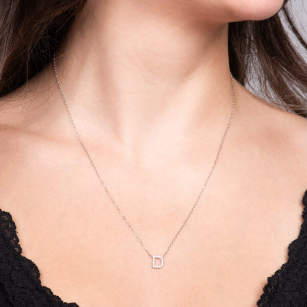 a woman wearing a necklace with the letter d on it