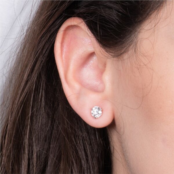 a woman's ear with a single diamond in it