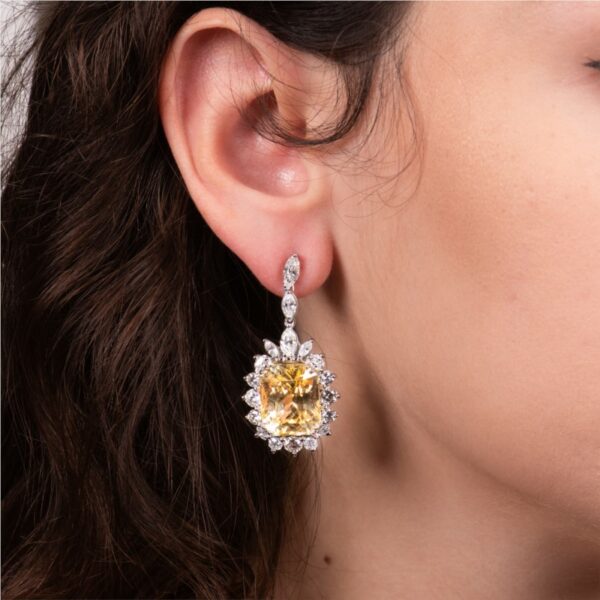 a woman wearing a pair of yellow and white diamond earrings