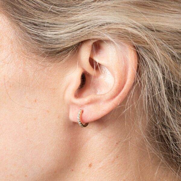 a woman's ear is shown with a single diamond in the middle