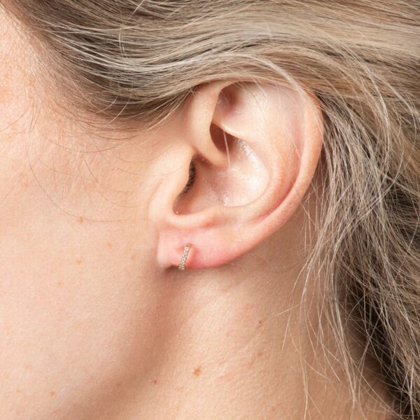 a woman's ear with a single diamond in the middle