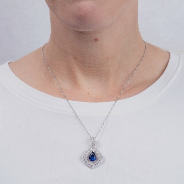 a woman wearing a necklace with a blue tear shaped pendant