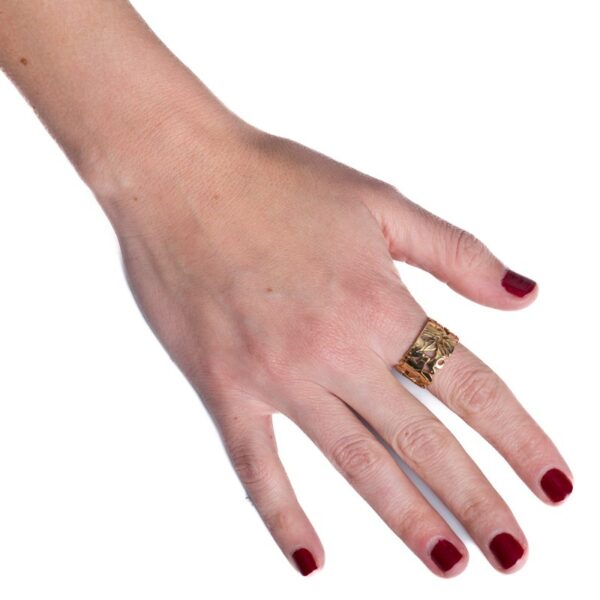 a woman's hand with red nail polish holding a gold ring