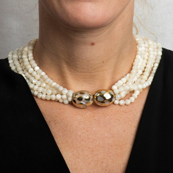a woman wearing a necklace with pearls