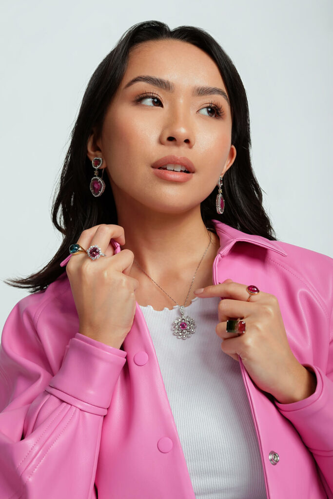 a woman in a pink jacket is holding onto her earrings