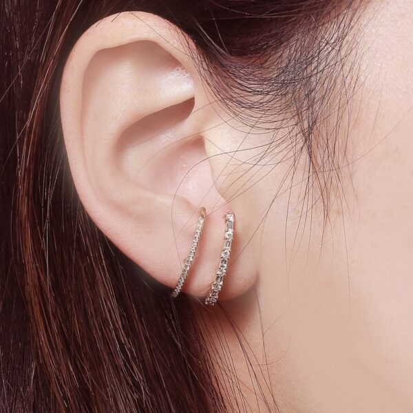 a woman wearing a pair of diamond hoop earrings