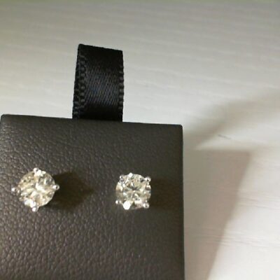 a pair of diamond earrings sitting on top of a black box