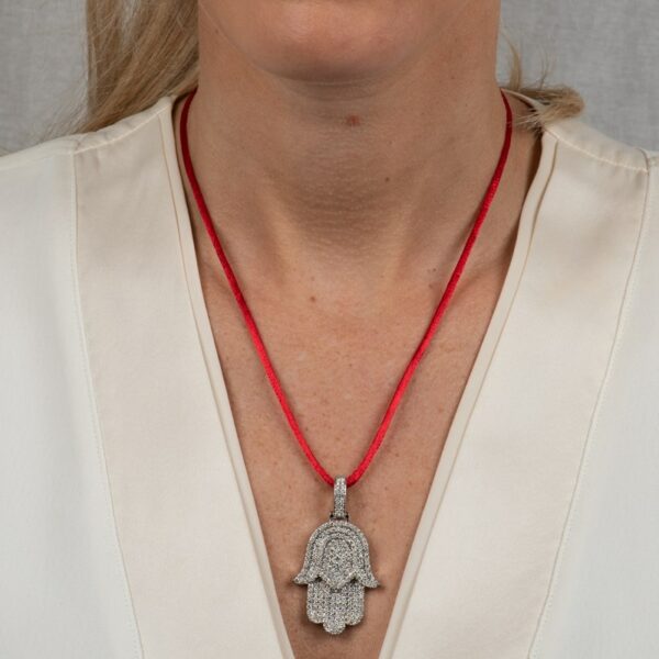 a woman wearing a necklace with a hamsa pendant on it