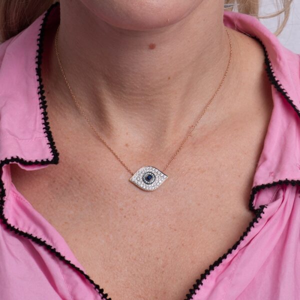 a woman wearing a pink shirt and a necklace with an evil eye on it