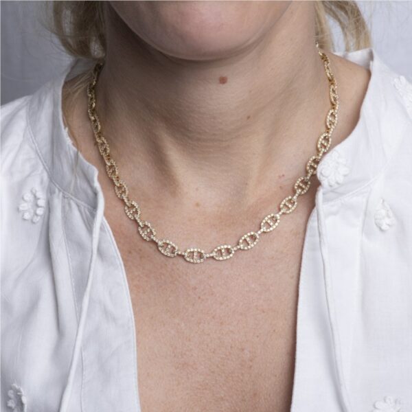 a woman wearing a gold necklace and white shirt