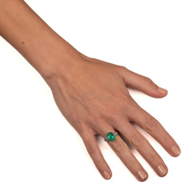 a person's hand with a green ring on it