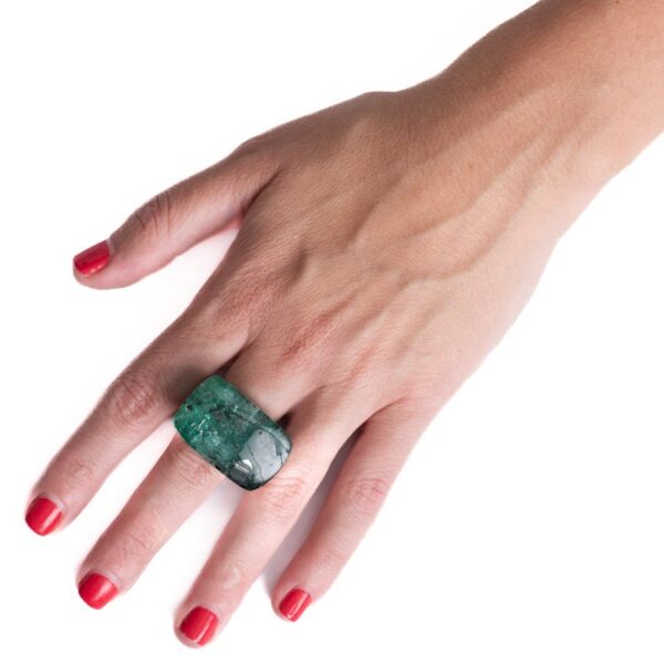 a woman's hand holding a green stone ring