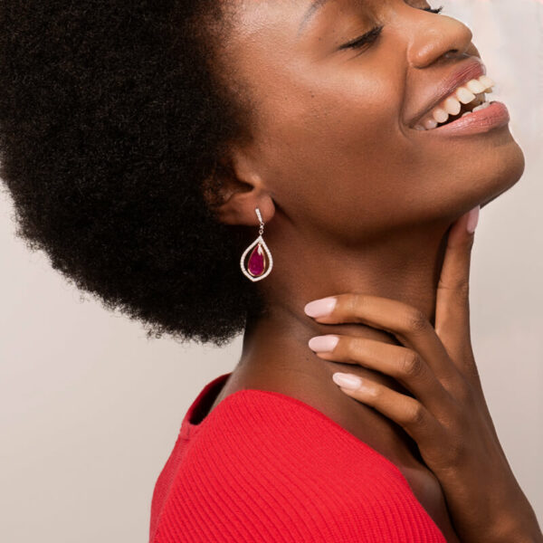 a woman with an afro is smiling and wearing earrings