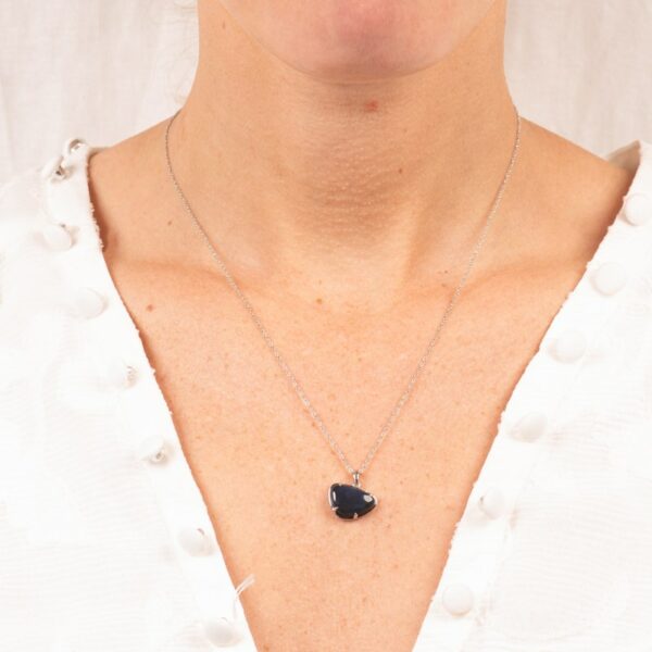 a woman wearing a necklace with a black stone on it