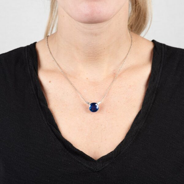 a woman wearing a necklace with a blue stone