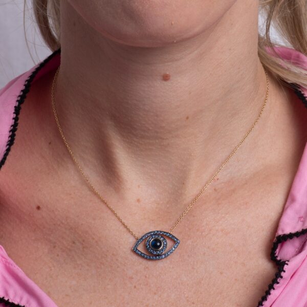 a woman wearing a necklace with an evil eye on it