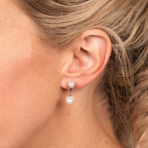 a woman wearing a pair of earrings with pearls