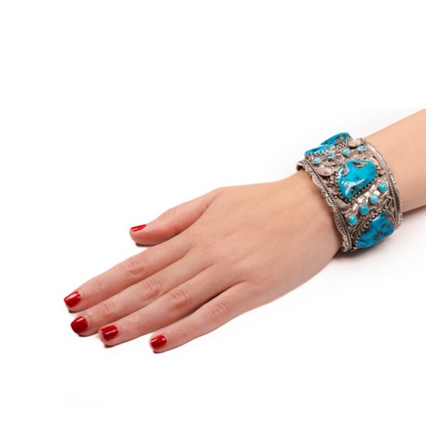 a woman's hand with red nails and a blue bracelet
