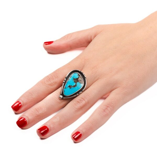 a woman's hand wearing a ring with a turquoise stone
