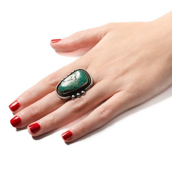a woman's hand with red nail polish and a green ring
