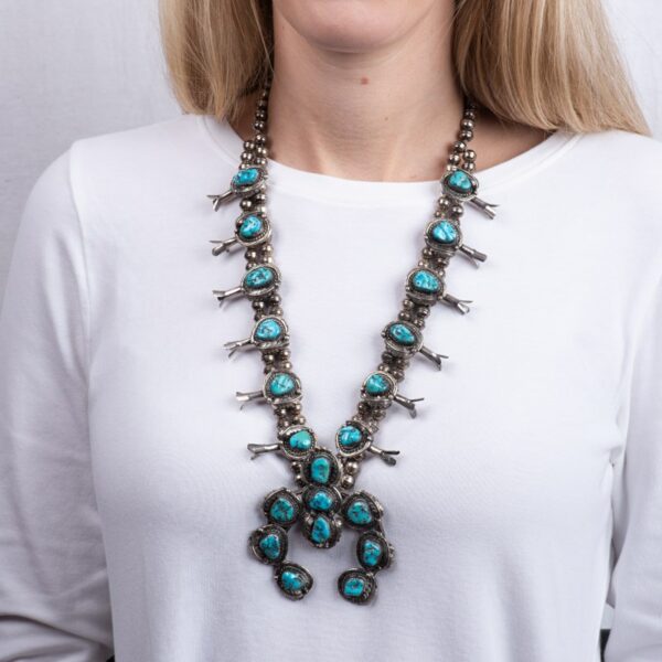 a woman wearing a necklace with turquoise stones