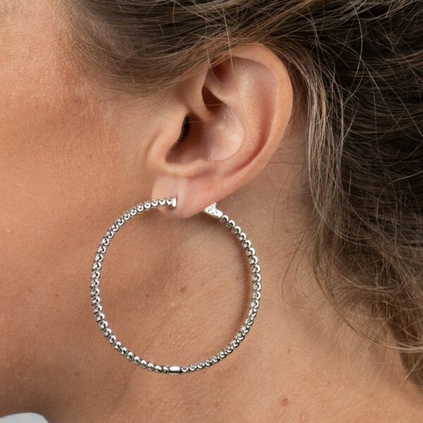 a close up of a person wearing large silver hoop earrings