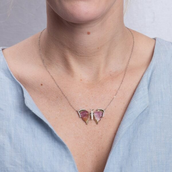 a woman wearing a necklace with two butterflies on it