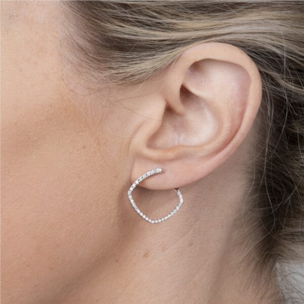 a woman wearing a pair of diamond hoop earrings
