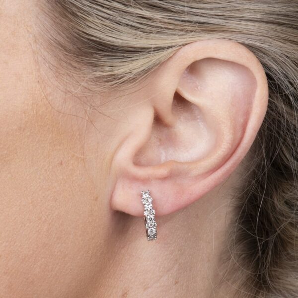 a close up of a woman's ear wearing a diamond earrings
